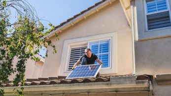 A Man Inspecting a Photovoltaic Panel on the Roof