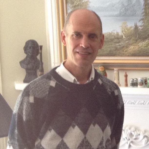 Charles dressed in an Argyll sweater with painting in the background